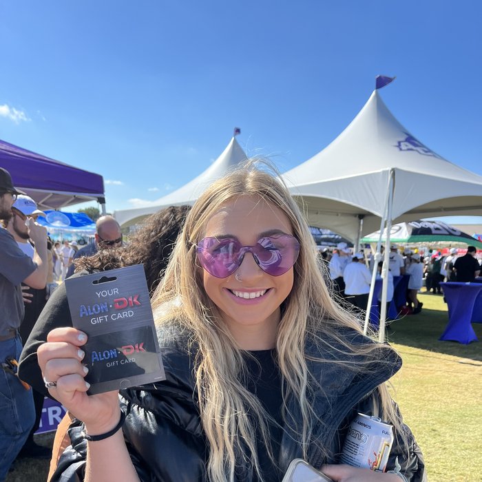 Fan holding an Alon/DK gift card at an ACU tailgate